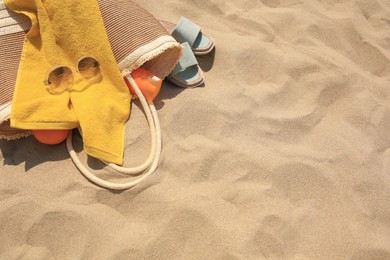 Beach bag, sunglasses and other accessories on sand, top view. Space for text