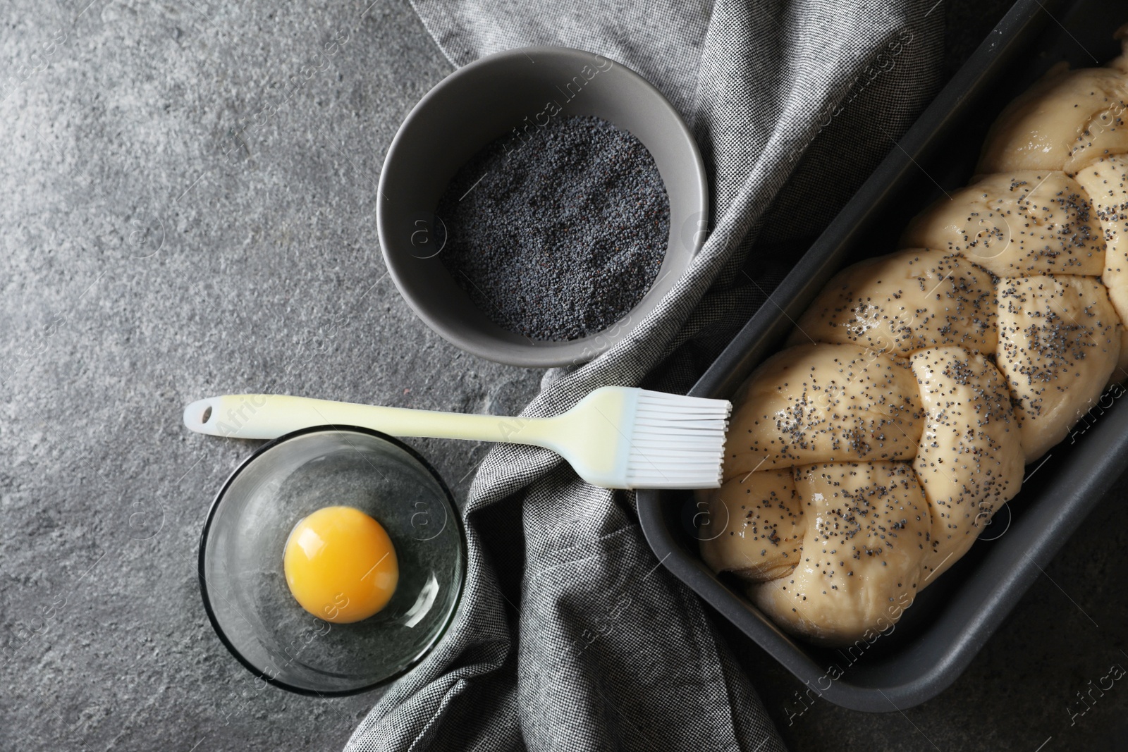 Photo of Homemade braided bread and ingredients on grey table, flat lay. Cooking traditional Shabbat challah