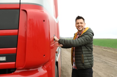 Portrait of happy driver opening door of modern truck outdoors