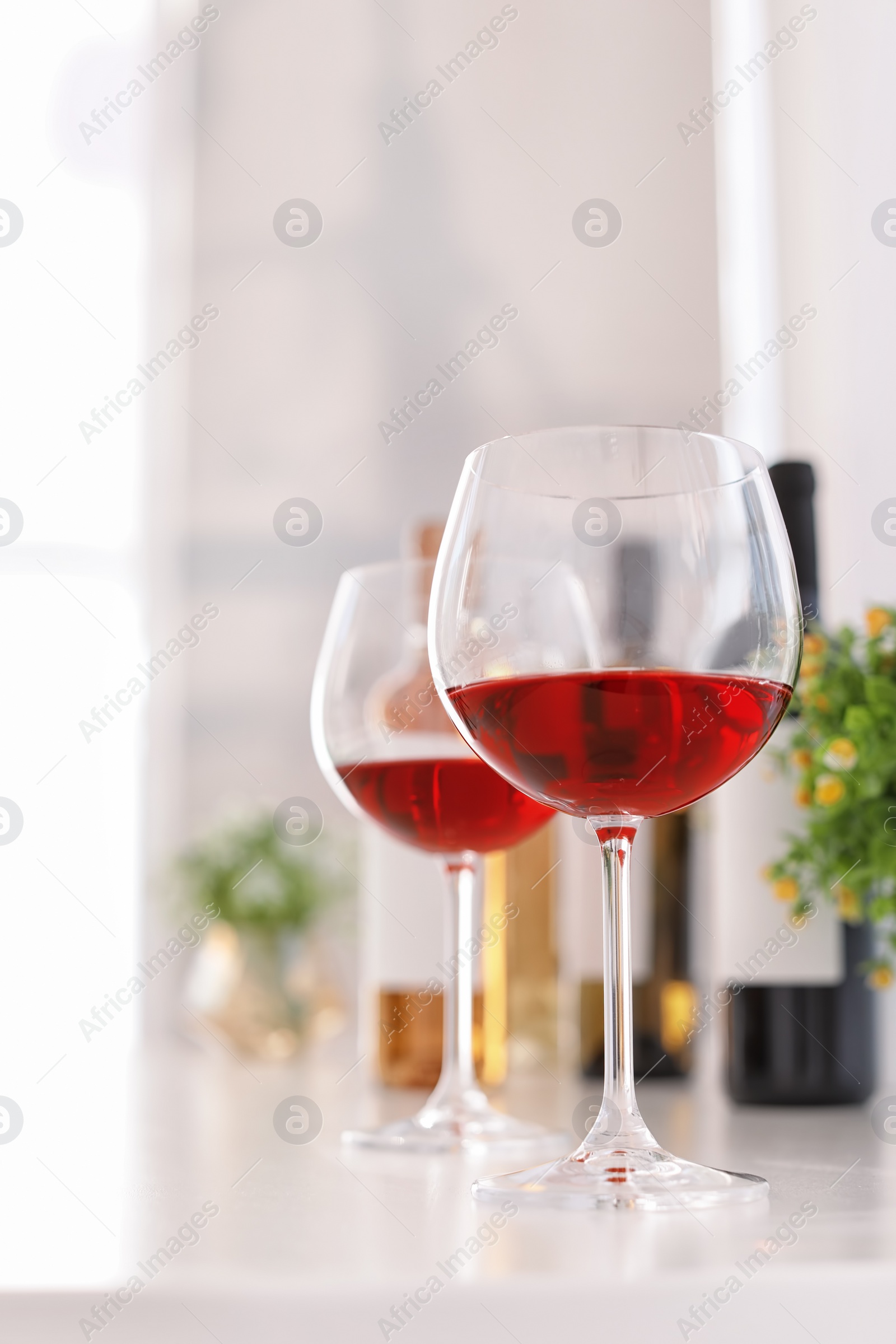 Photo of Glasses and bottles with delicious wine on table indoors