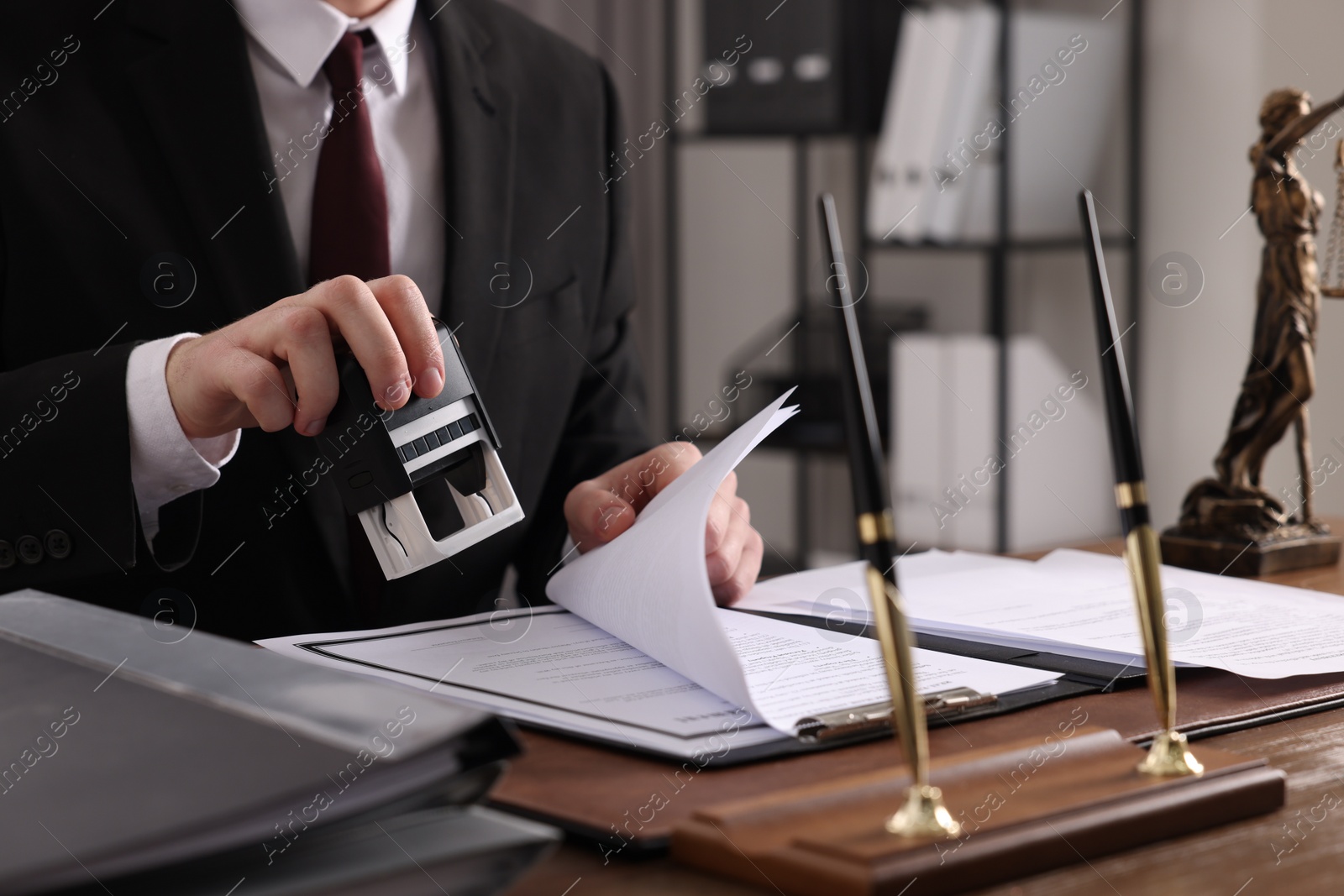 Photo of Notary stamping document at table in office, closeup