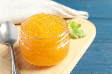 Fresh pike caviar in glass jar on blue wooden table, closeup. Space for text