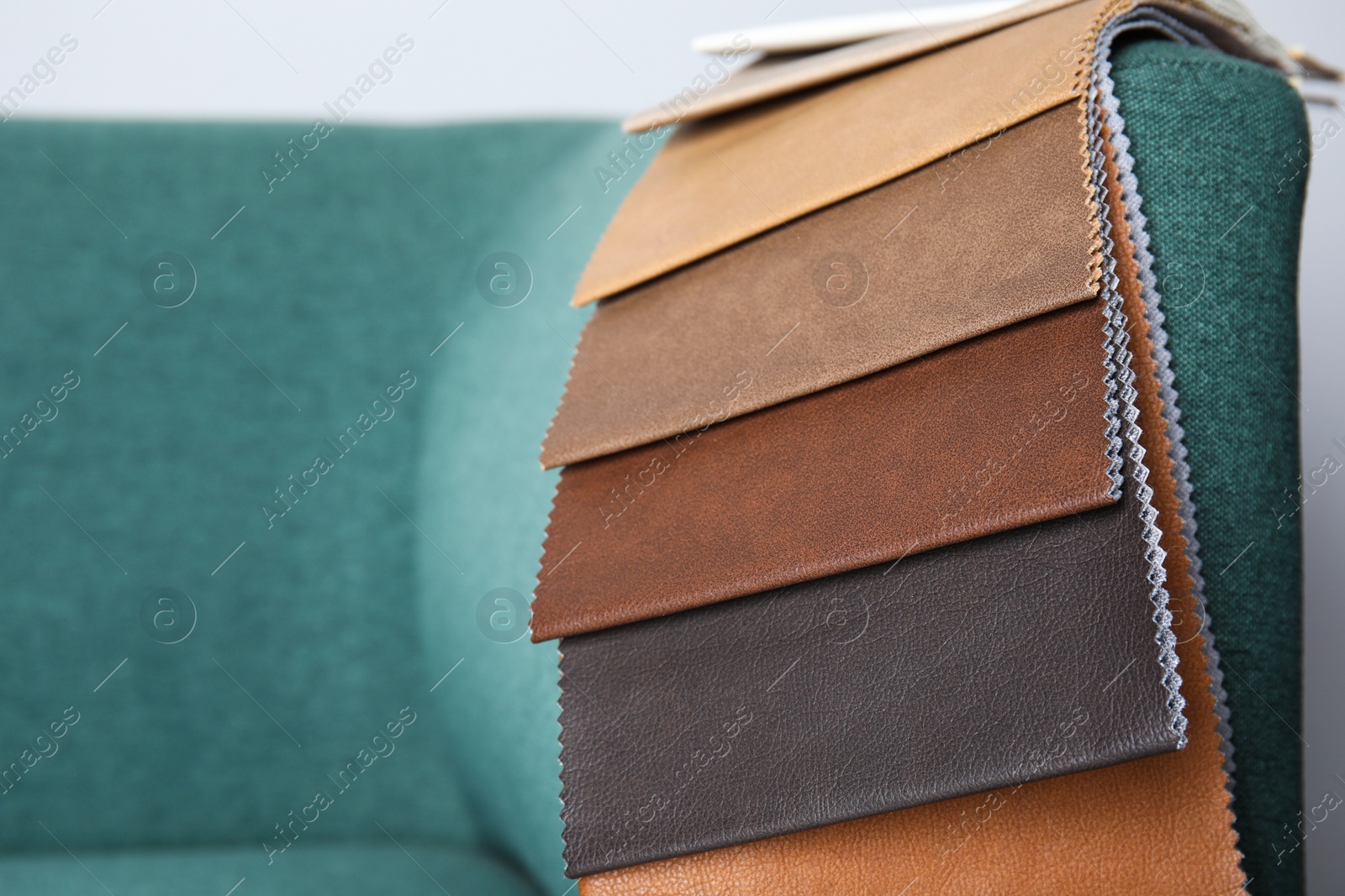 Photo of Catalog of colorful fabric samples on green sofa, closeup. Space for text