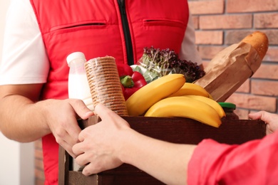 Photo of Male courier delivering food to client indoors, closeup