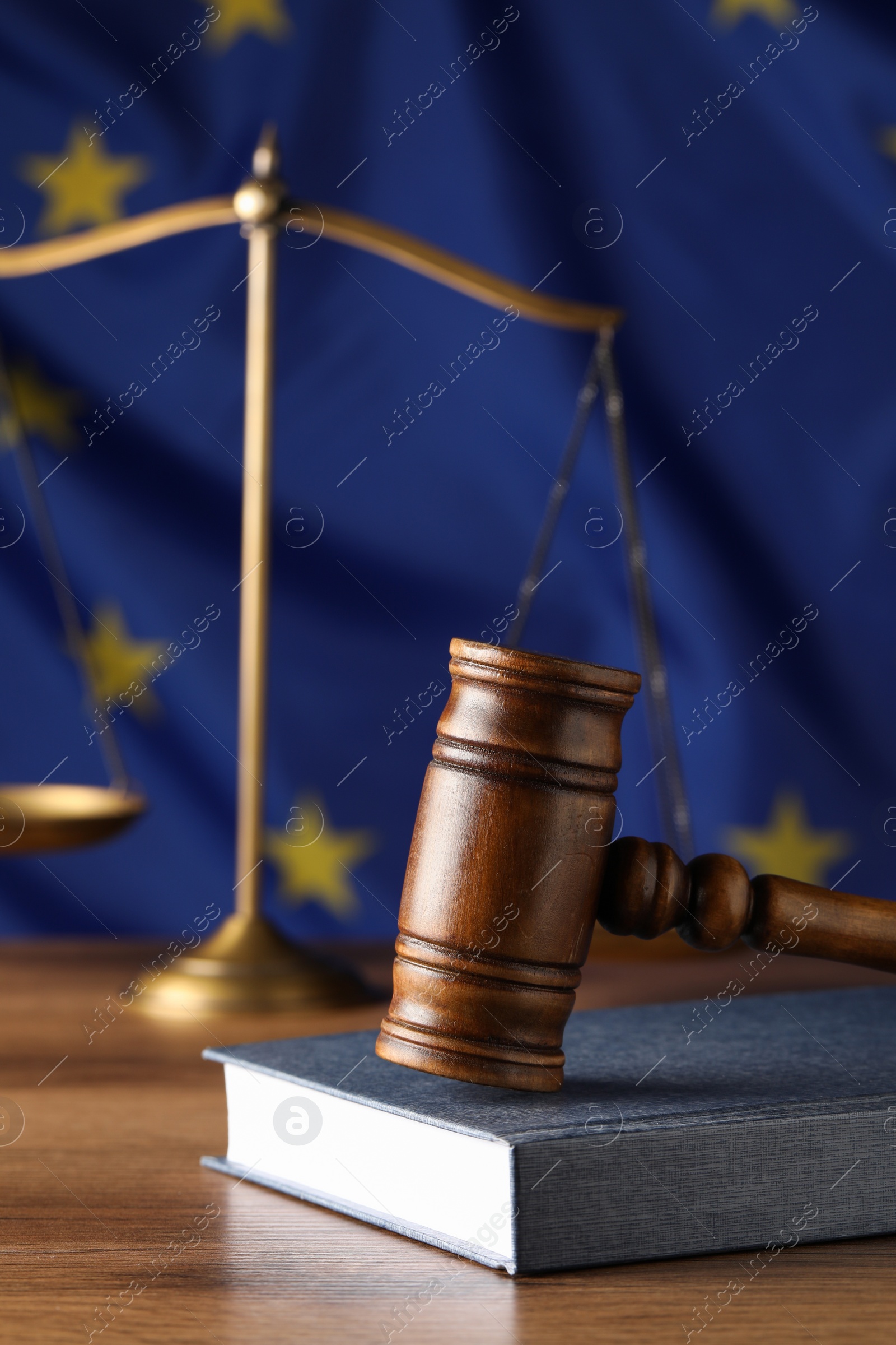 Photo of Judge's gavel and book on wooden table against European Union flag