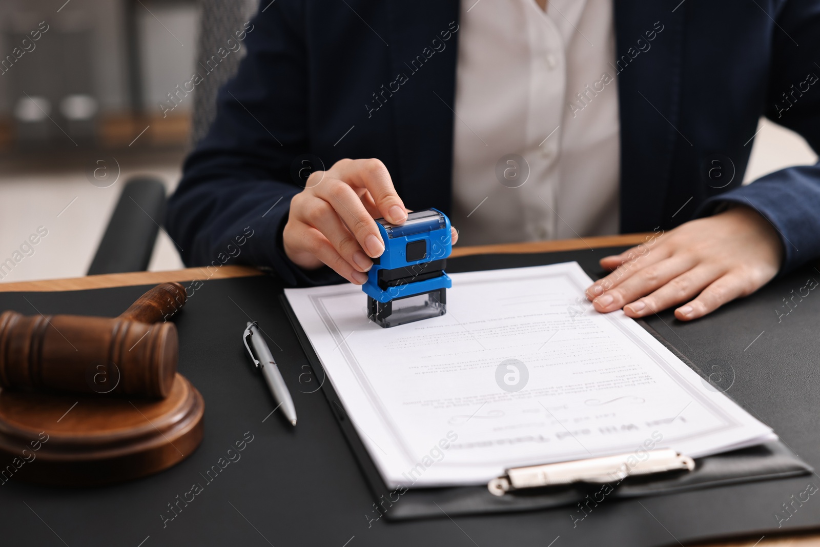 Photo of Notary stamping document at table in office, closeup