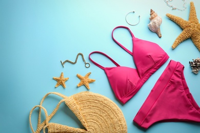 Photo of Beautiful pink bikini and beach accessories on light blue background, flat lay. Space for text