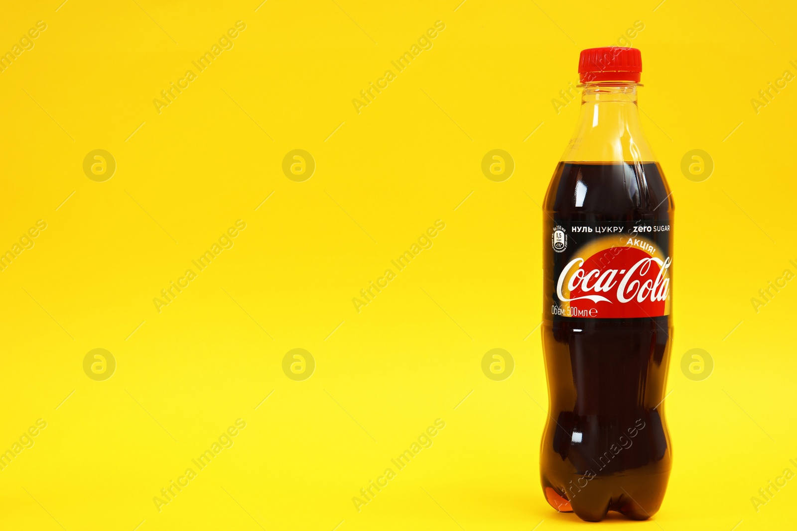 Photo of MYKOLAIV, UKRAINE - NOVEMBER 14, 2018: Bottle of Coca-Cola on color background. Space for text