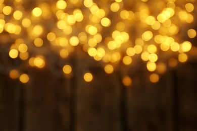 Photo of Blurred view of Christmas lights on wooden background, space for text