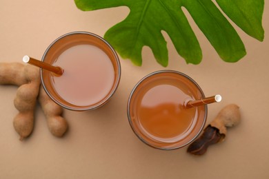 Photo of Tamarind juice, fresh fruits and green leaf on pale brown background, flat lay