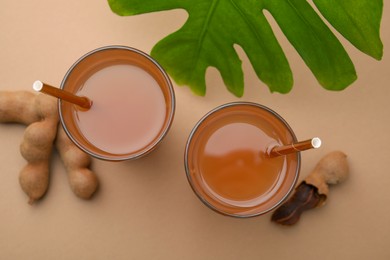 Tamarind juice, fresh fruits and green leaf on pale brown background, flat lay