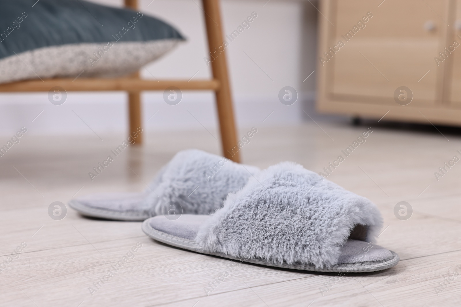 Photo of Grey soft slippers on light wooden floor indoors, closeup