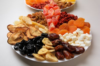 Photo of Plates with different dried fruits on white background