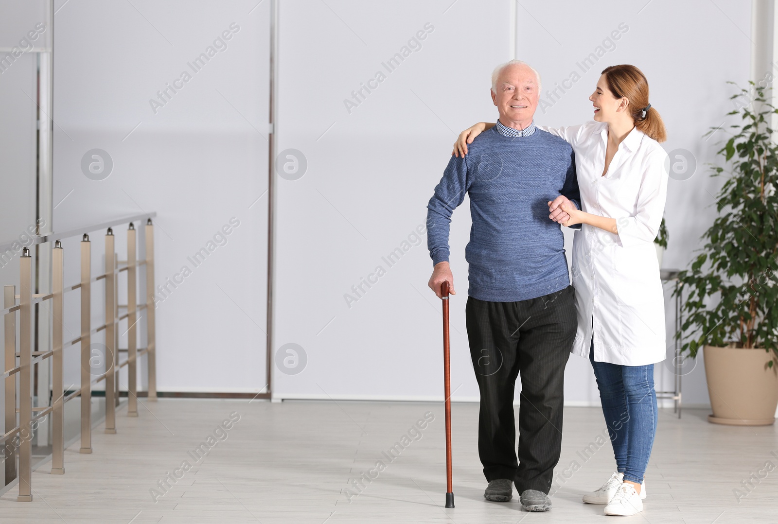 Photo of Elderly man with female caregiver indoors. Space for text