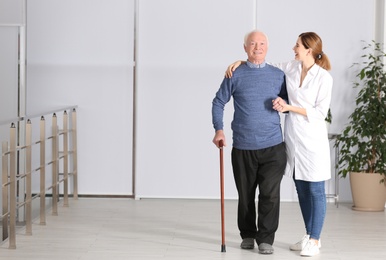 Elderly man with female caregiver indoors. Space for text