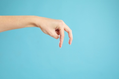 Woman imitating walk with hand on light blue background, closeup. Finger gesture