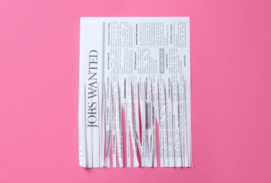 Half shredded newspaper on pink background, top view