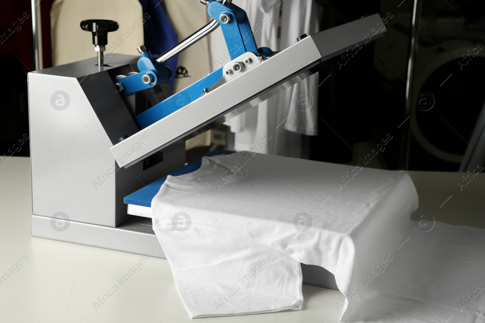 Photo of Printing logo. Heat press with t-shirt on white table