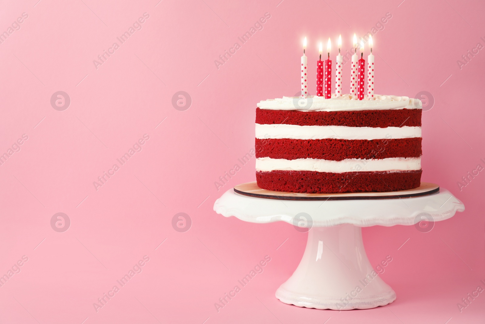 Photo of Delicious homemade red velvet cake with candles on pink background. Space for text