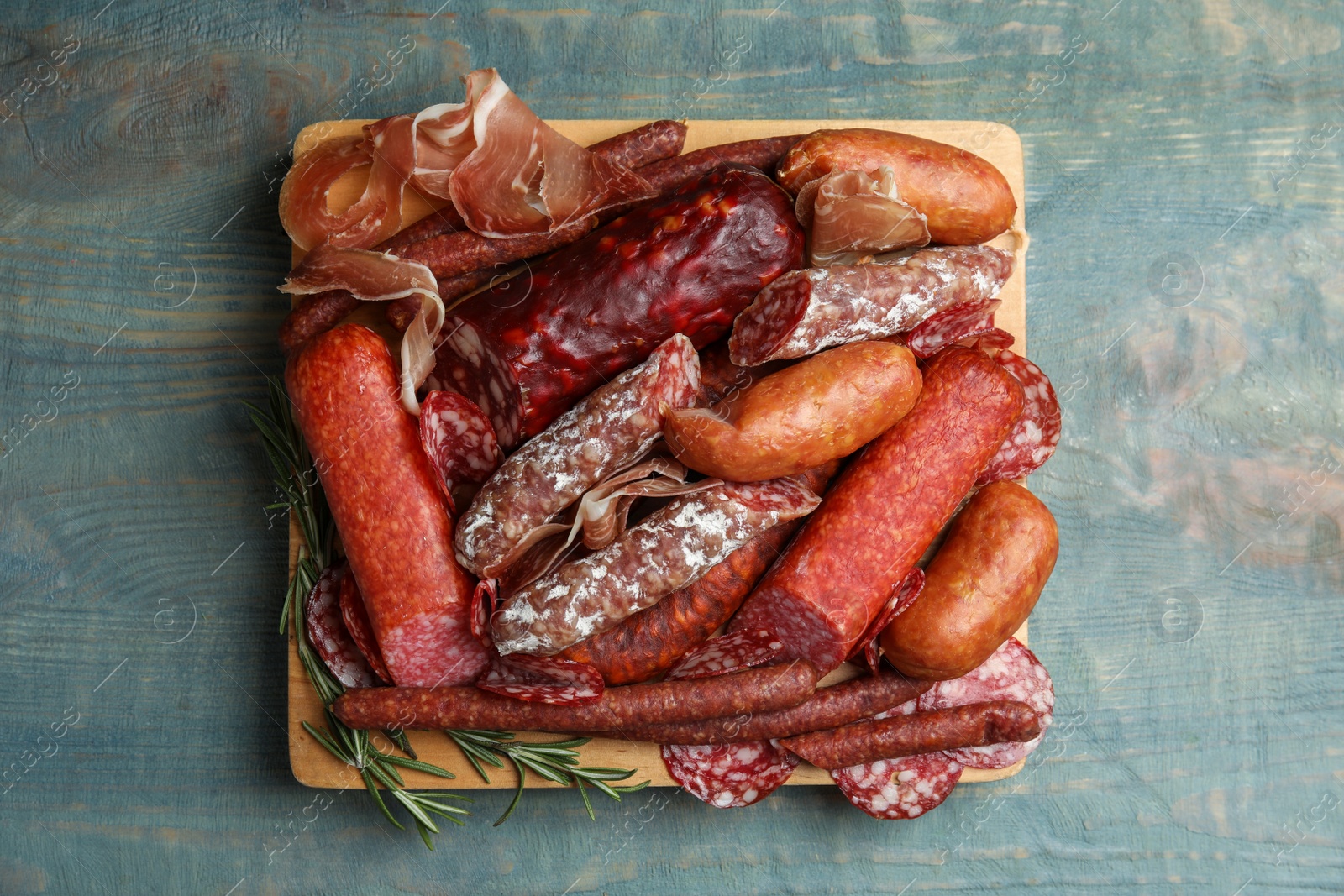 Photo of Different types of sausages served on light blue wooden table, top view