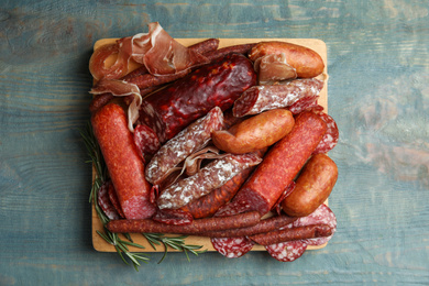 Different types of sausages served on light blue wooden table, top view