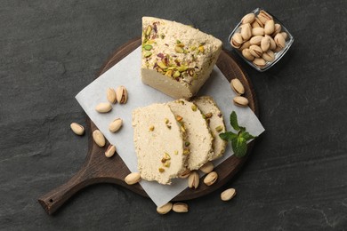 Photo of Tasty halva with pistachios and mint on grey table, top view