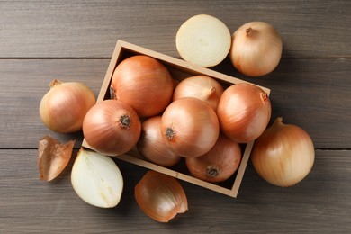 Photo of Whole and cut onions on wooden table, flat lay