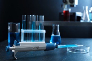 Laboratory analysis. Micropipette, petri dish, beaker, flask and test tubes on black table