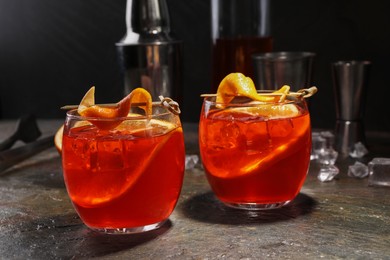 Photo of Aperol spritz cocktail, ice cubes and orange slices in glasses on grey textured table