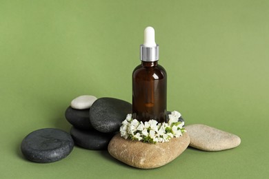 Photo of Composition with bottle of face serum, spa stones and beautiful flowers on light green background