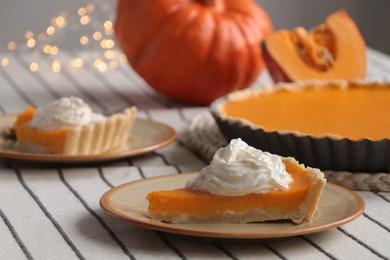 Piece of fresh homemade pumpkin pie with whipped cream on table