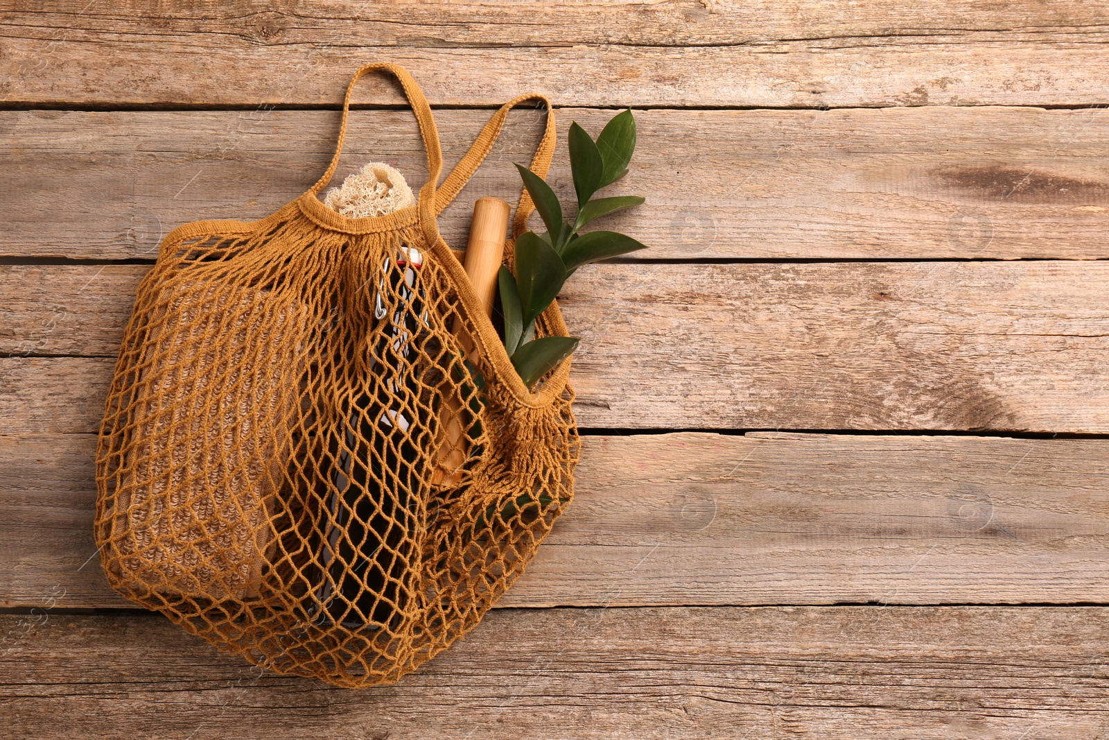 Photo of Net bag with different items on wooden table, top view and space for text. Conscious consumption