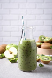 Photo of Delicious kiwi smoothie and fresh fruits on light table