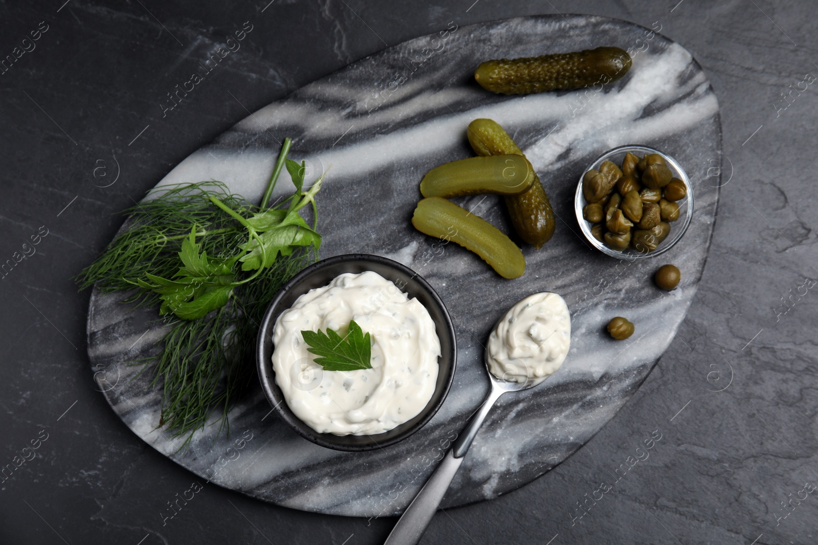 Photo of Tasty tartar sauce and ingredients on black table, top view