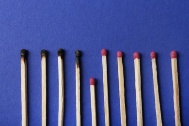 Photo of Burnt and whole matches on blue background, flat lay. Stop destruction concept