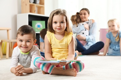 Photo of Cute little children with book indoors, space for text. Learning and playing