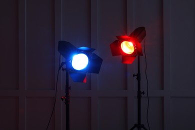 Photo of Bright red and blue spotlights near wall in dark room
