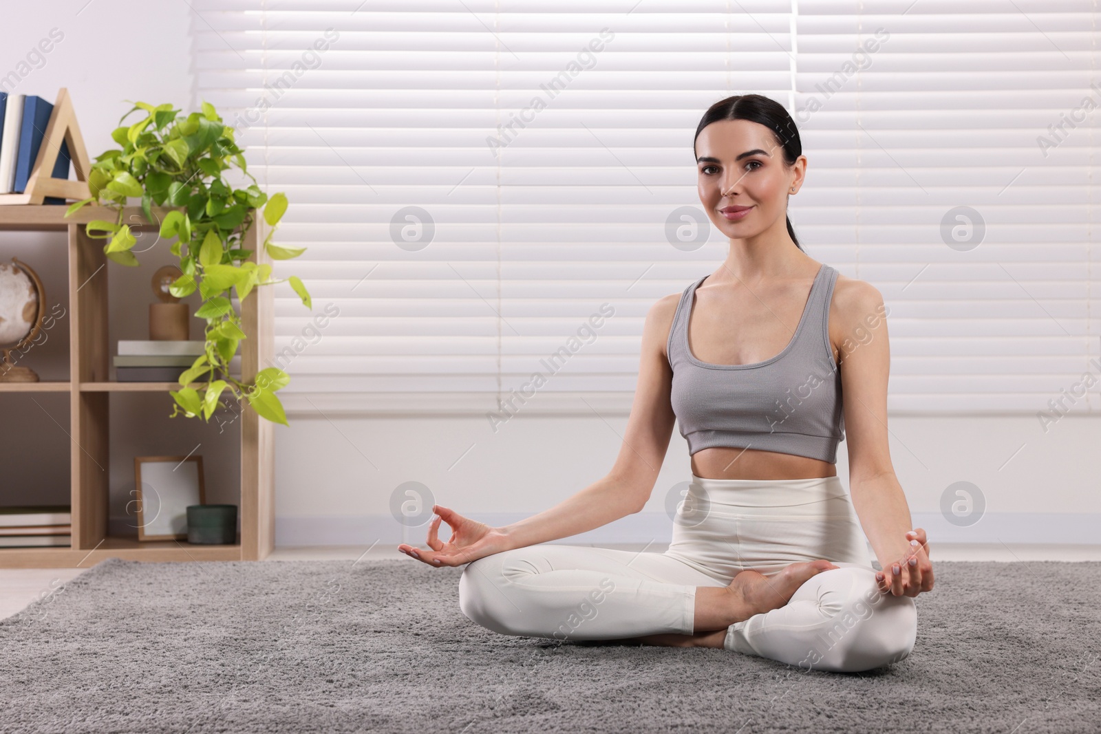 Photo of Woman in sportswear meditating at home., space for text