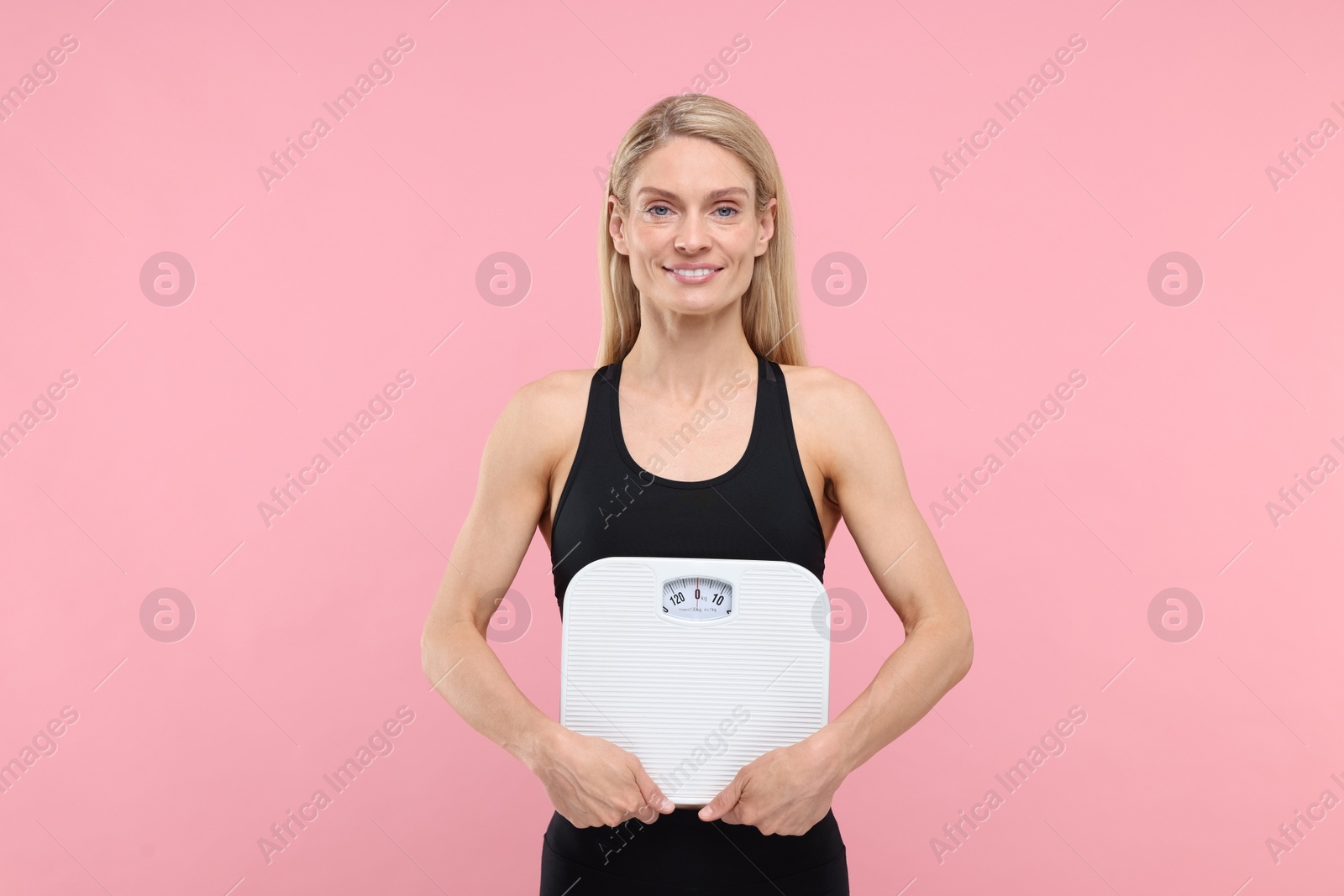 Photo of Slim woman holding scales on pink background. Weight loss