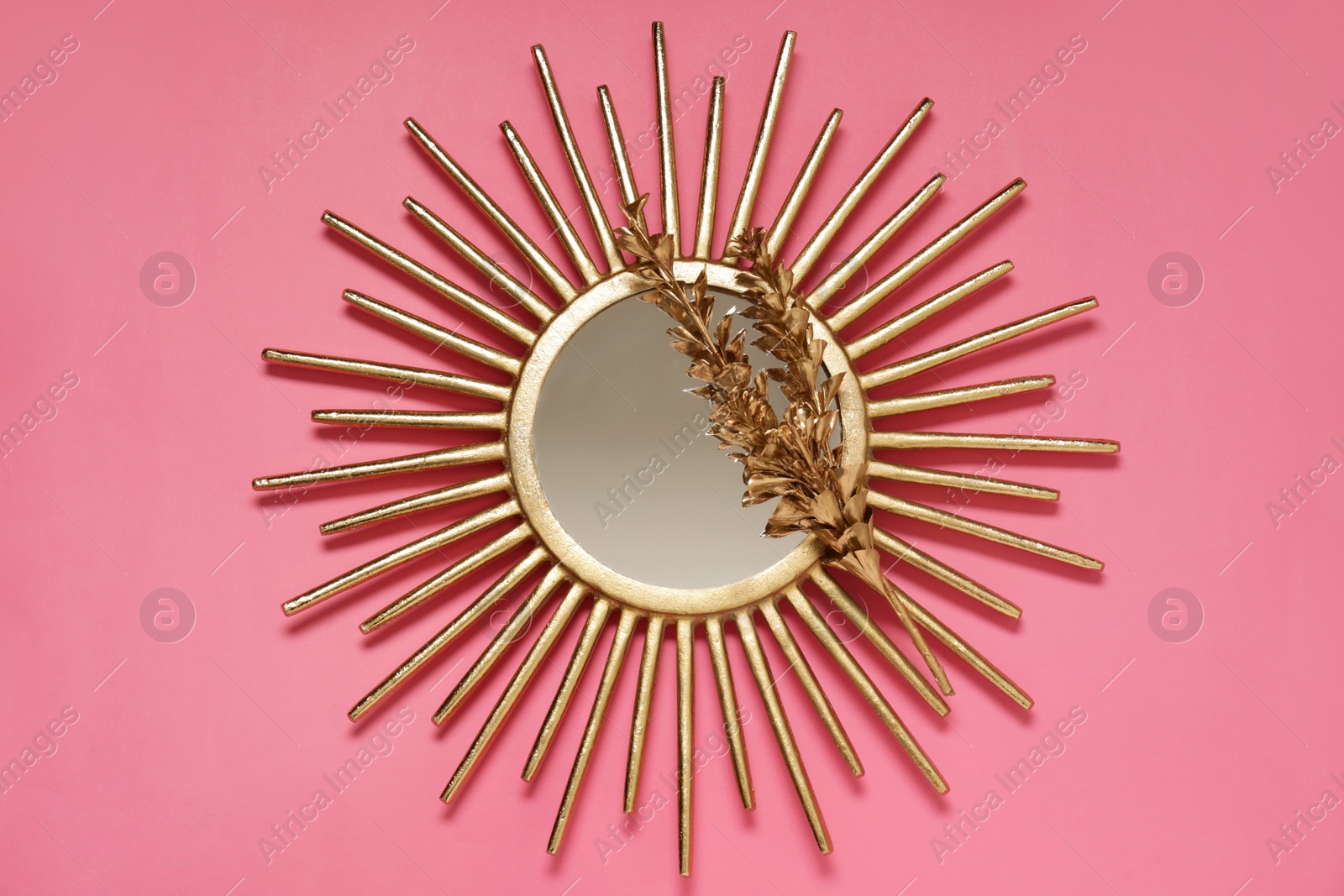 Photo of Golden mirror and dried flower on pink background, top view