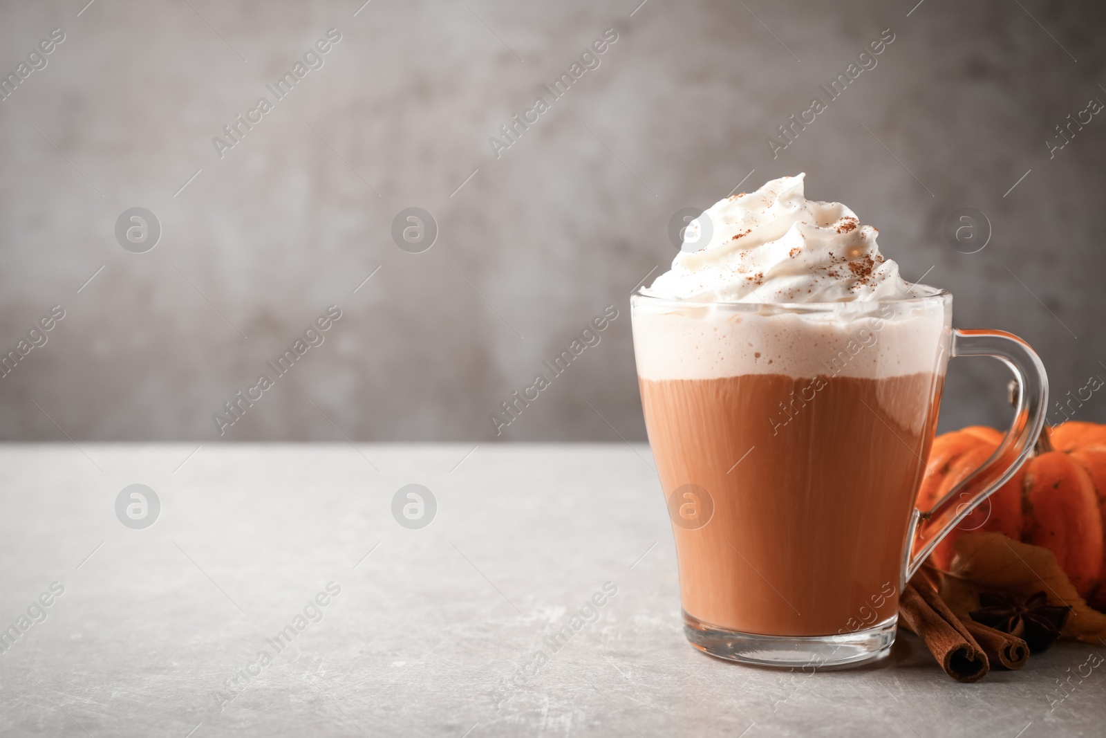 Photo of Delicious pumpkin latte on grey table, closeup. Space for text