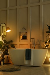 Photo of Stylish bathroom interior with houseplants and string lights. Home design
