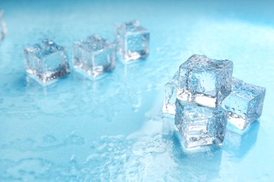Photo of Crystal clear ice cubes on light blue background. Space for text