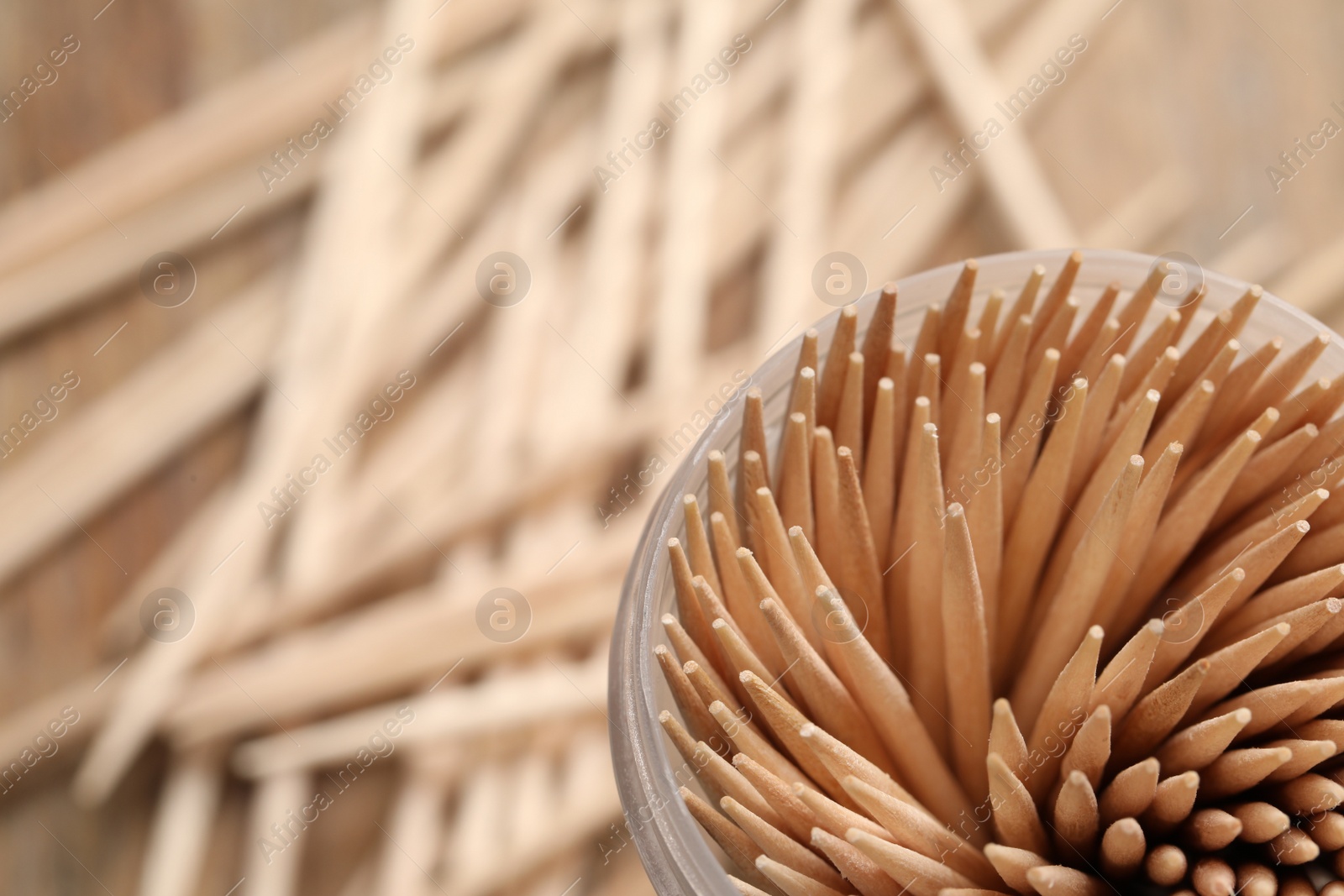 Photo of Wooden toothpicks in holder, closeup. Space for text
