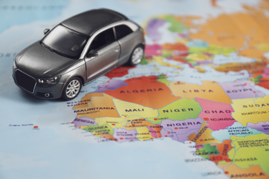 Photo of Grey toy car on world map. Trip planning