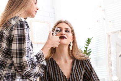 Professional makeup artist working with beautiful young woman in studio