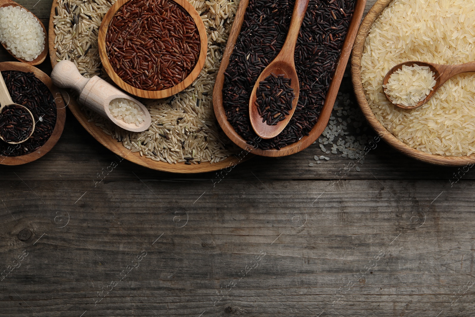 Photo of Different sorts of rice on wooden table, flat lay. Space for text