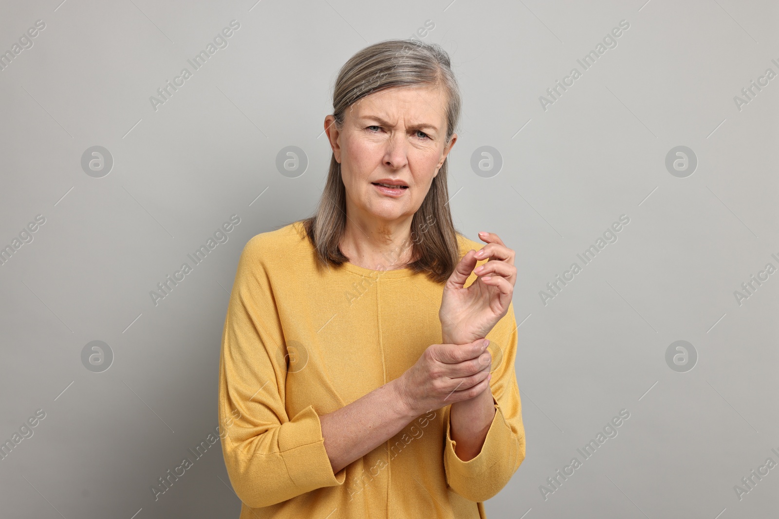 Photo of Arthritis symptoms. Woman suffering from pain in wrist on gray background