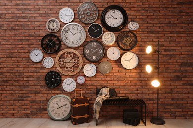 Collection of clocks hanging on red brick wall indoors