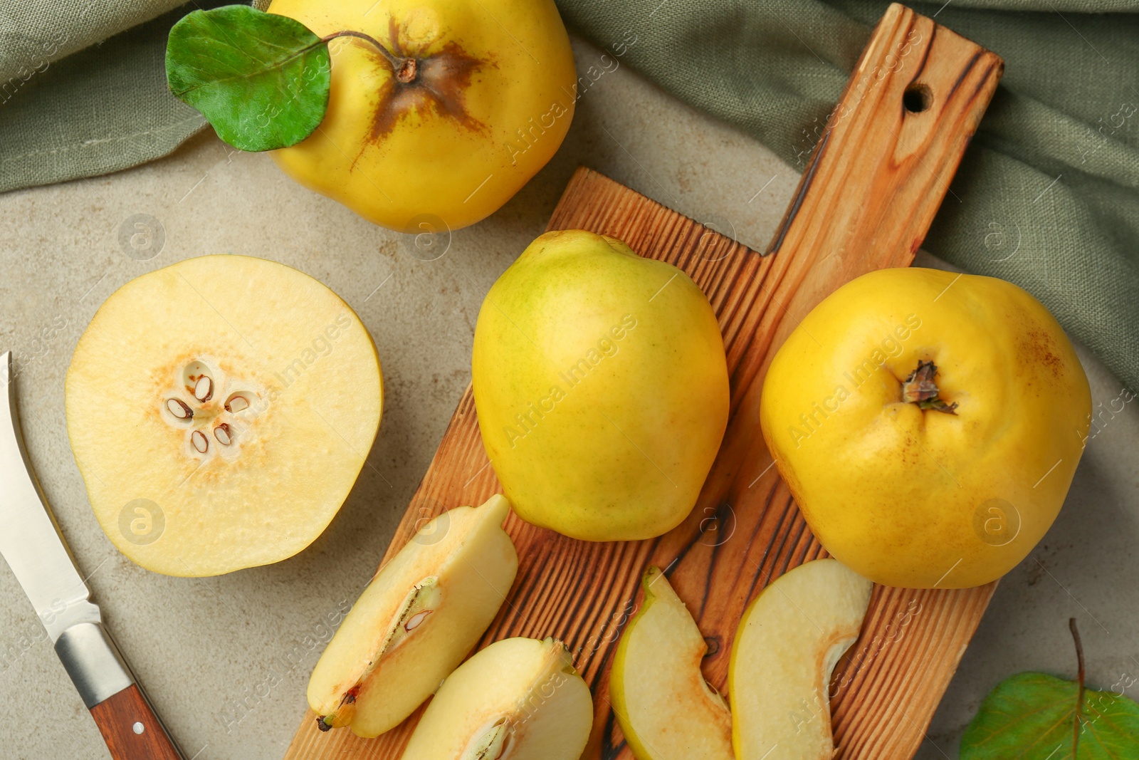 Photo of Tasty ripe quince fruits and knife on grey table, flat lay